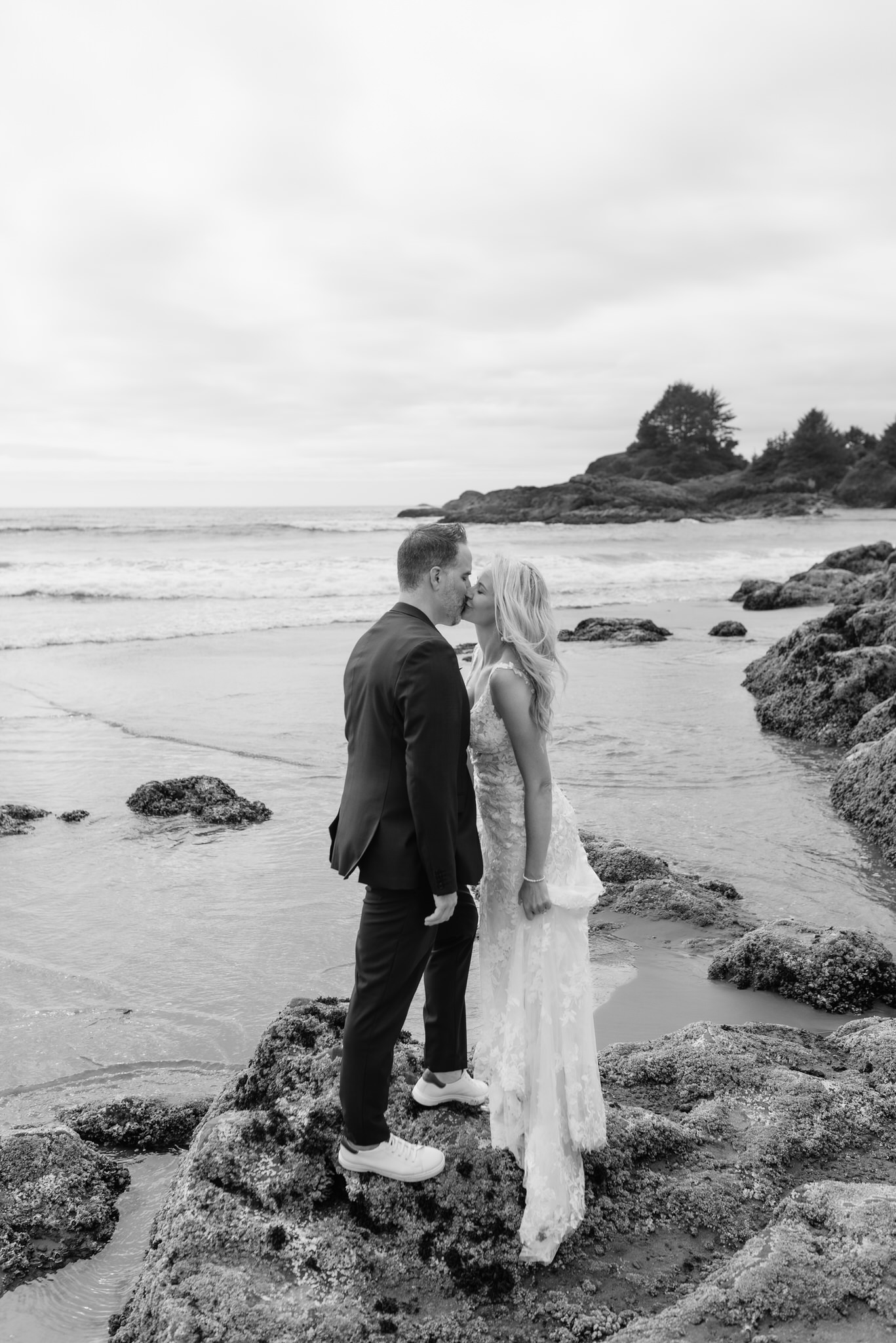 A bride and groom kiss on the beach outside of Pacific Sands