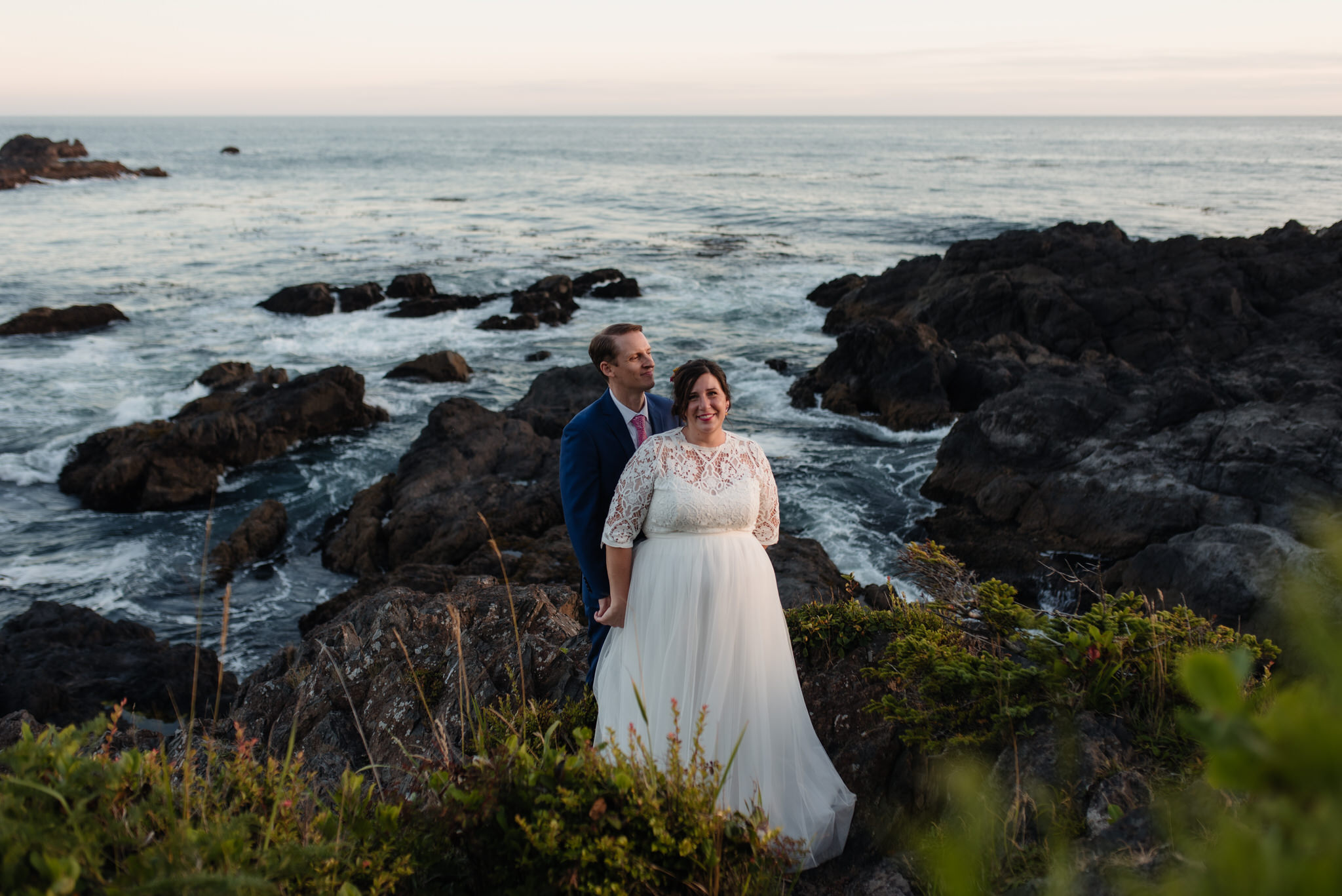 The bride and groom at golden hour with the crashing waves behind them